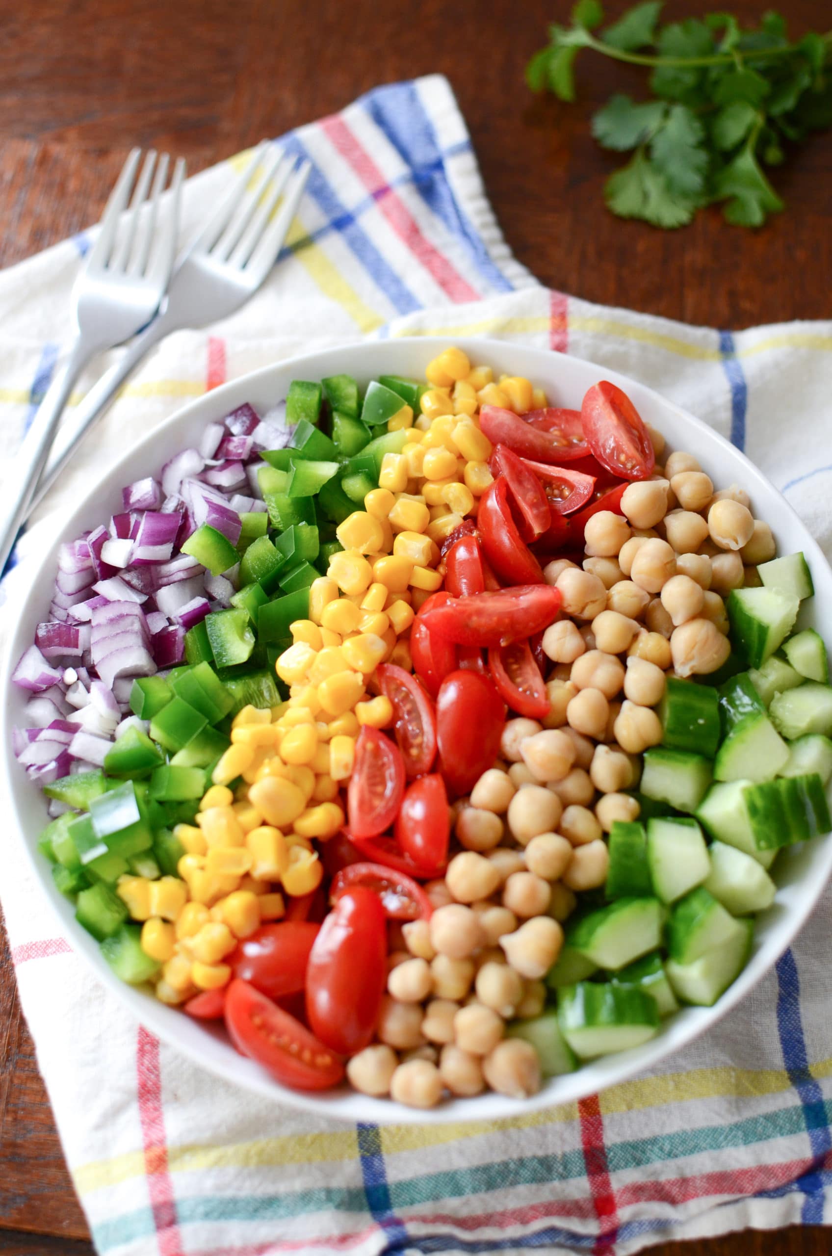 Ingredients for a vegan salad in a bowl, arranged in rainbow like stripes.