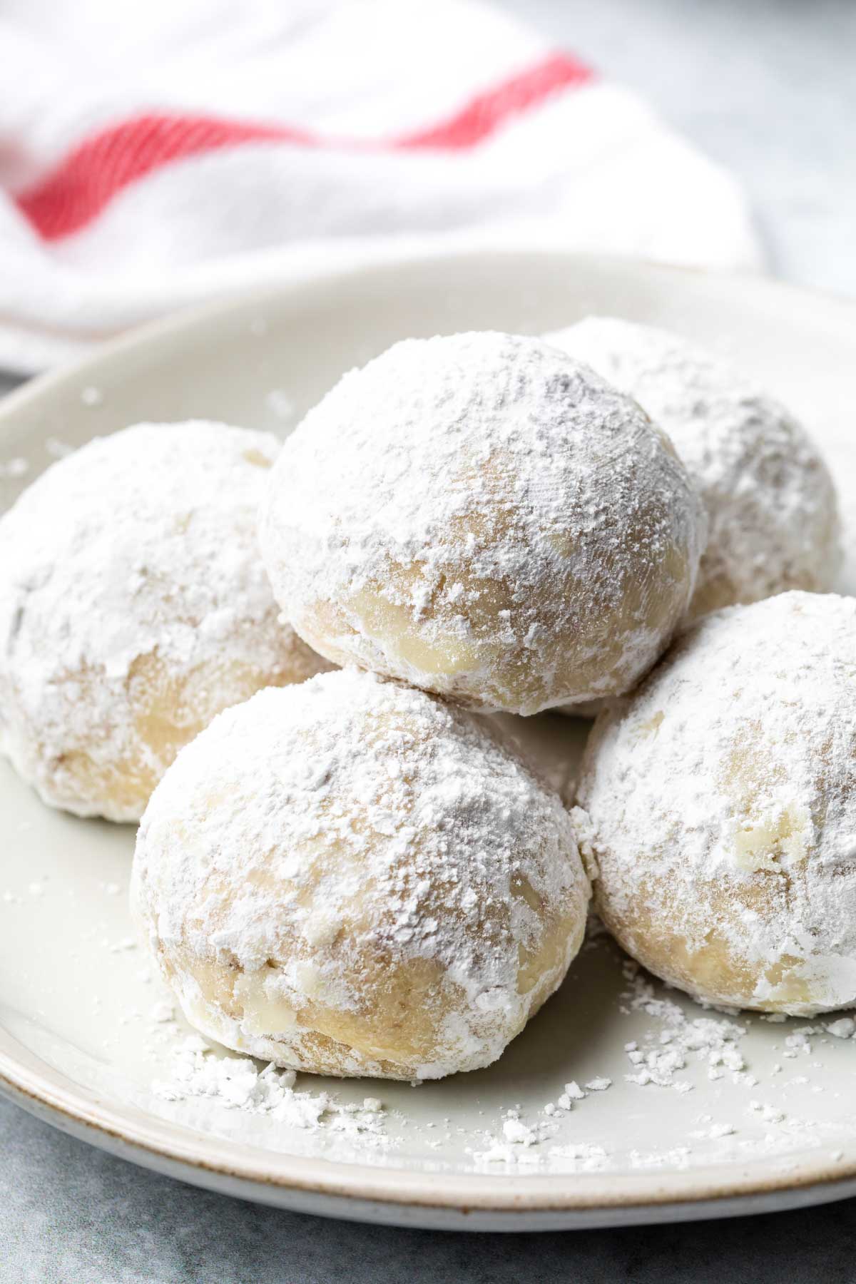 closeup of pecan snowball cookies piled on a small plate