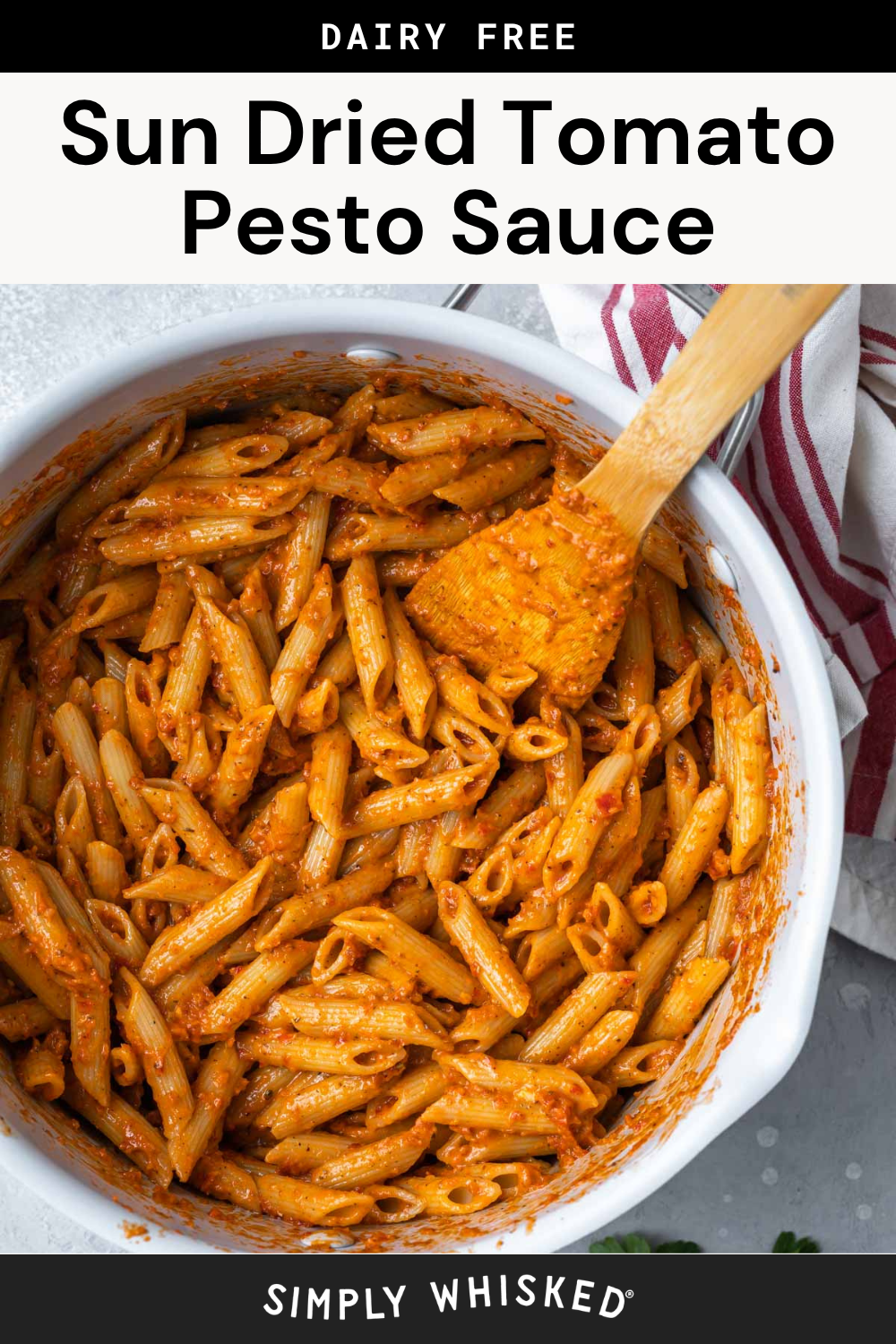 A pot of penne pasta mixed with flavorful sun dried tomato pesto sauce, stirred with a wooden spatula. A red and white striped towel is next to the pot. Text above reads Sun Dried Tomato Pesto Sauce.