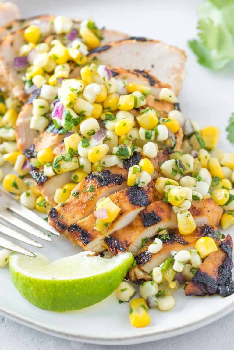 tequila lime chicken topped with corn salsa on a light gray plate, vintage fork and lime wedge on the side of the plate
