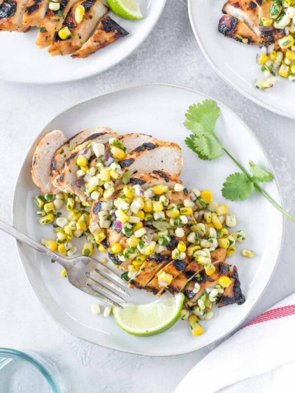tequila lime chicken topped with corn salsa on a light gray plate, vintage fork and lime wedge on the side of the plate