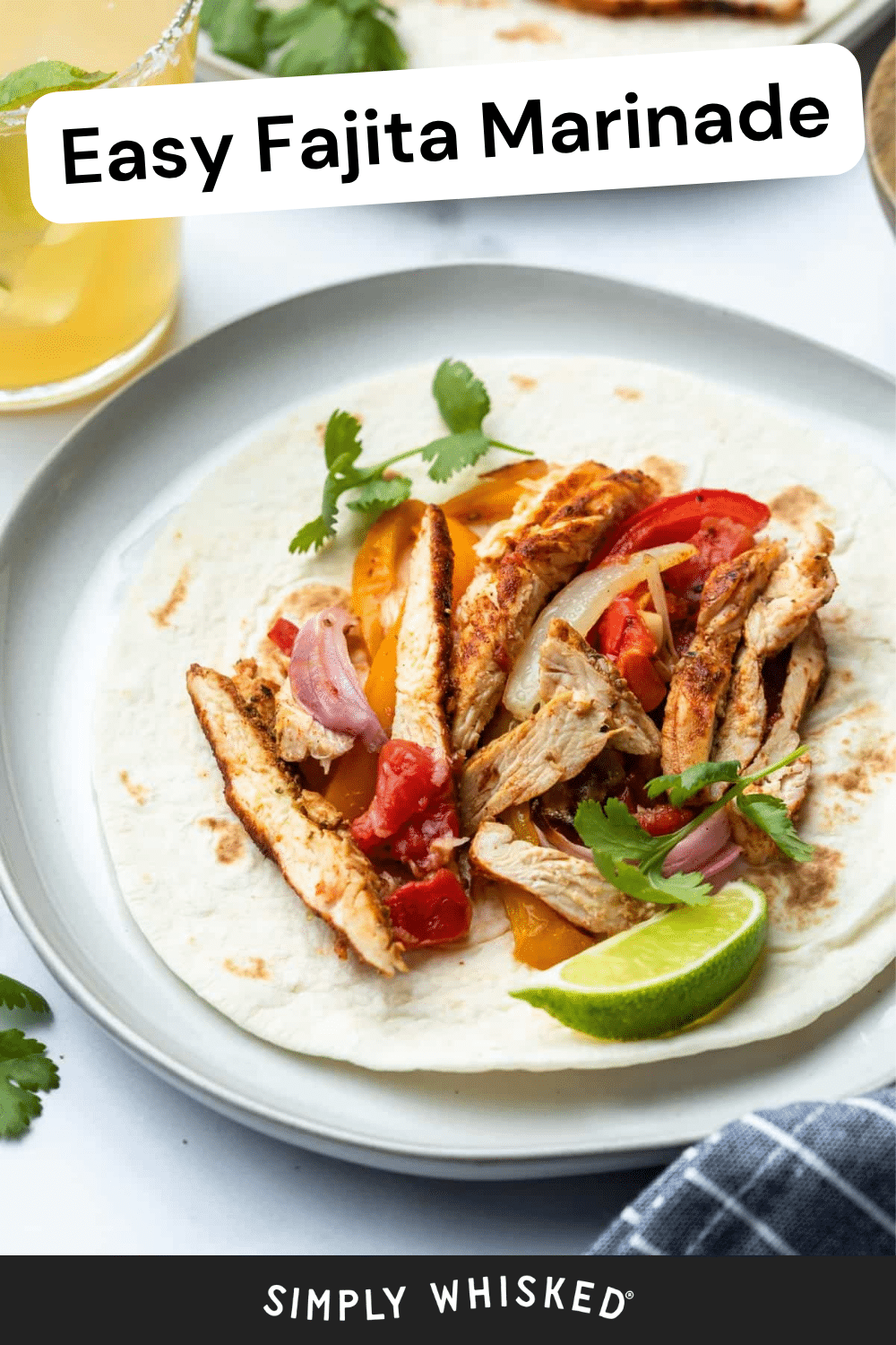 A flour tortilla topped with grilled chicken strips marinated in a flavorful fajita marinade, sautéed onions, bell peppers, tomato, cilantro, and a lime wedge, served on a plate next to a drink. Text reads Easy Fajita Marinade and Simply Whisked.