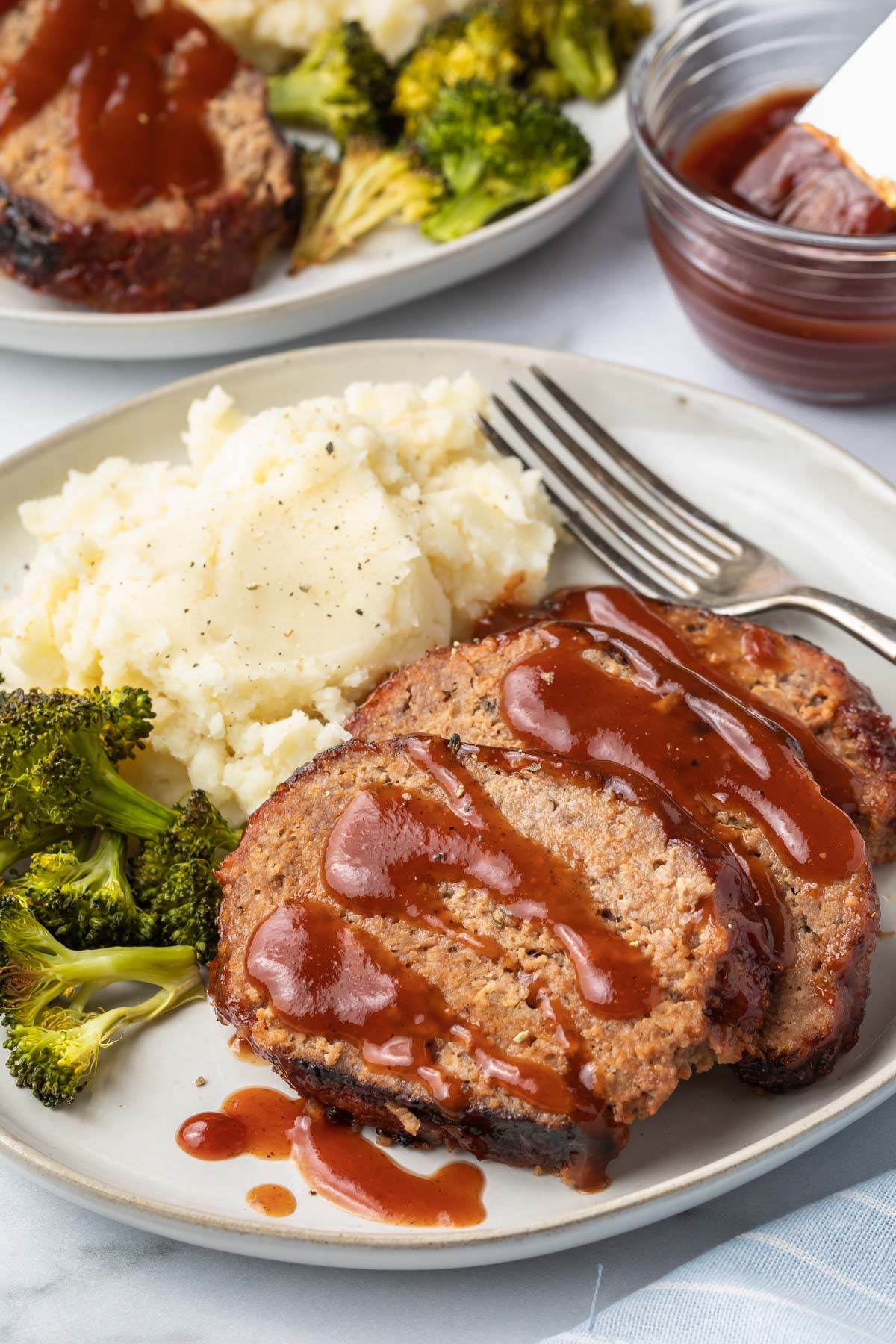 an upclose view of a plate with meatloaf, mashed potatoes and broccoli 