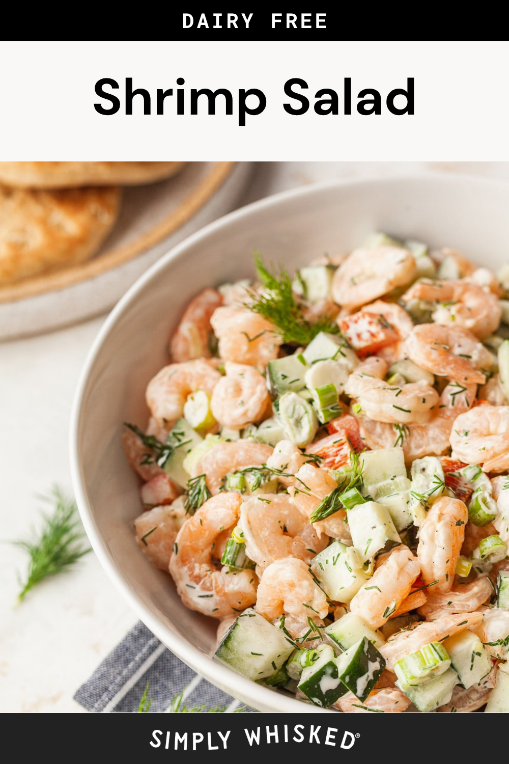 A bowl of shrimp salad with cucumbers, dill, and dressing sits on a table beside a plate of biscuits. The image is labeled dairy free shrimp salad and simply whisked, highlighting the fresh and flavorful ingredients that make this shrimp salad both delicious and satisfying.