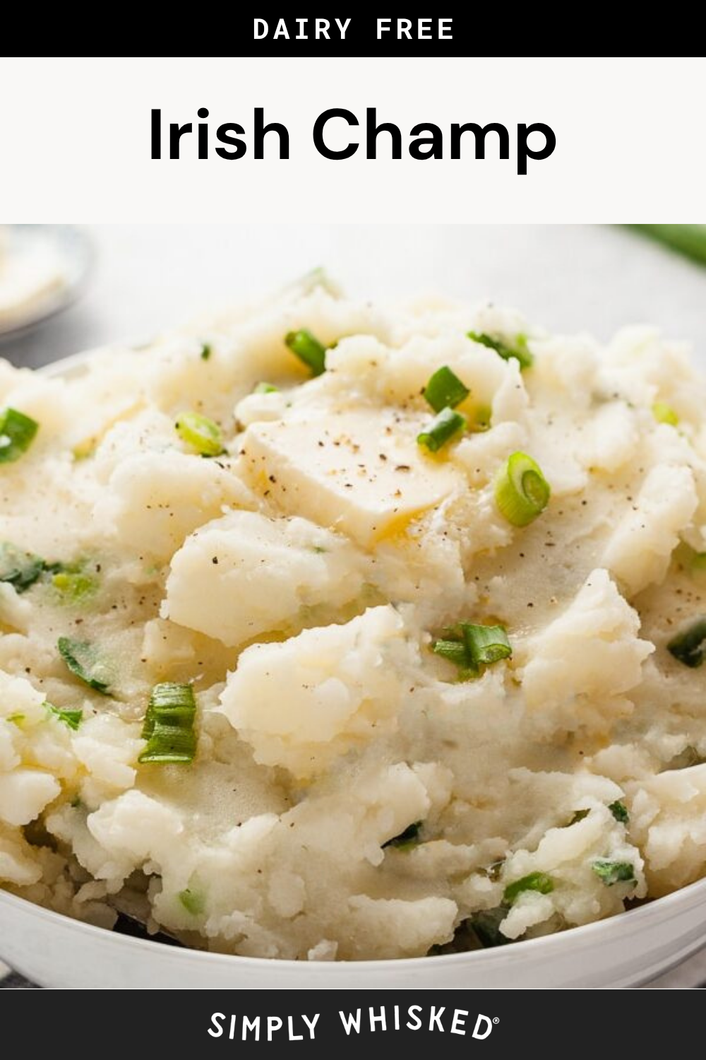 A bowl of classic Irish champ mashed potatoes, made dairy-free and topped with chopped green onions, black pepper, and a pat of dairy-free butter.