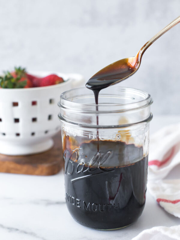 balsamic reduction (balsamic glaze) in a mason jar with a spoon above letting some drip back into the jar