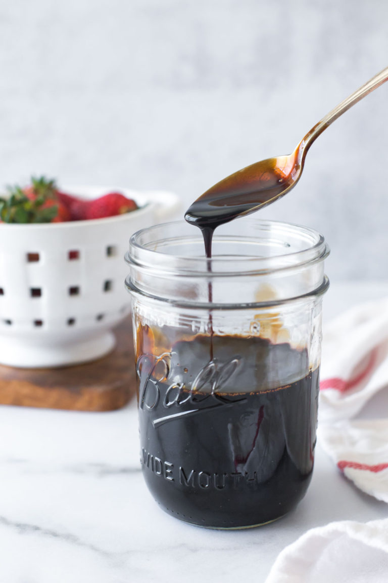 balsamic reduction (balsamic glaze) in a mason jar with a spoon above letting some drip back into the jar