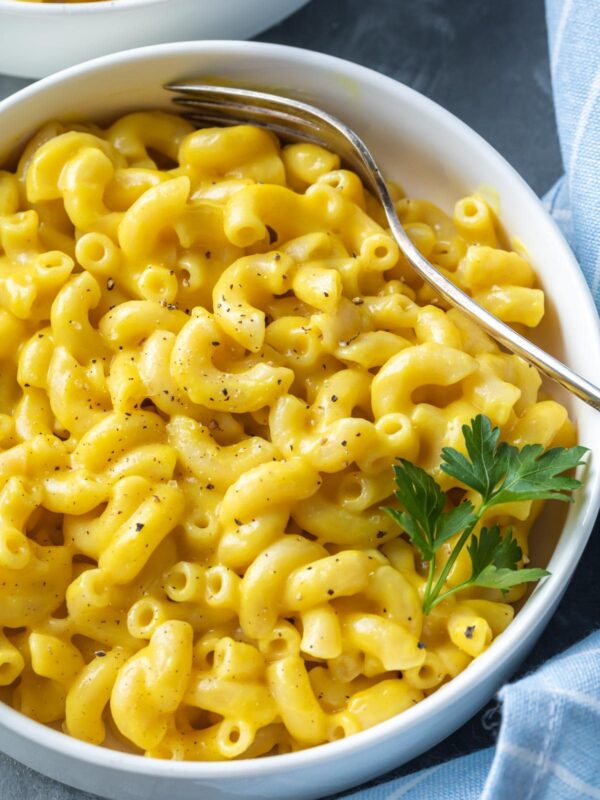 a close up view of mac and cheese with garnish and black pepper