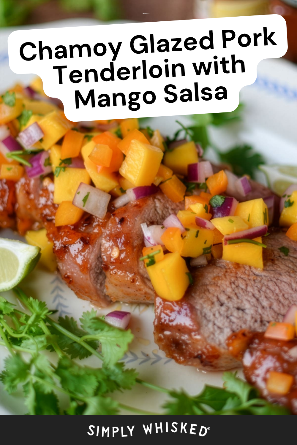 Chamoy glazed pork tenderloin, sliced and topped with colorful mango salsa, is garnished with fresh cilantro and a lime wedge, served elegantly on a white plate.