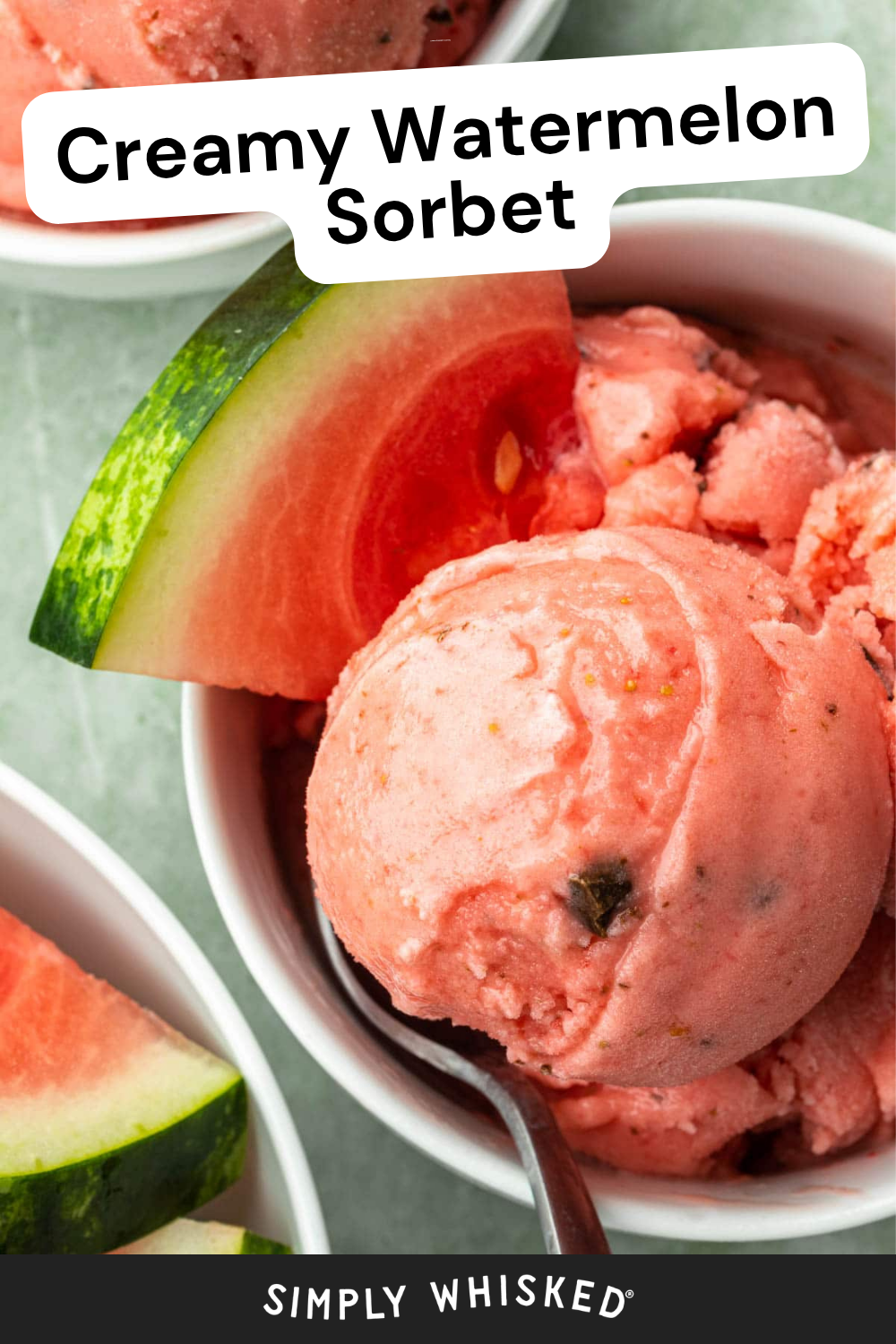 A bowl of creamy pink watermelon sorbet with a watermelon slice and a spoon, placed on a green surface. Text reads “Creamy Watermelon Sorbet” at the top and “Simply Whisked” at the bottom, highlighting this refreshing watermelon sorbet treat.