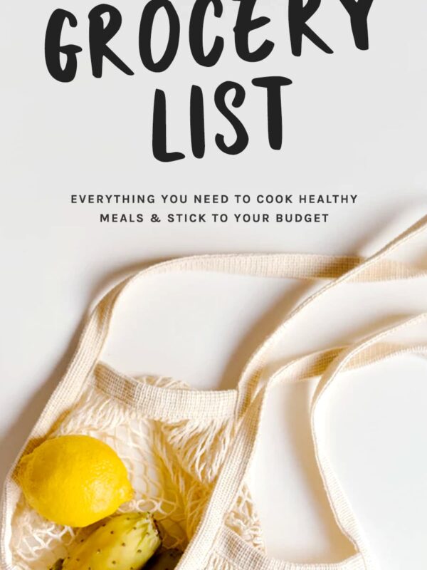 overhead image of woven grocery bag on a light gray surface with lemon and fruit coming out, optimized for Pinterest with text overlay that reads "basic grocery list: everything you need to cook healthy meals and stick to your budget"