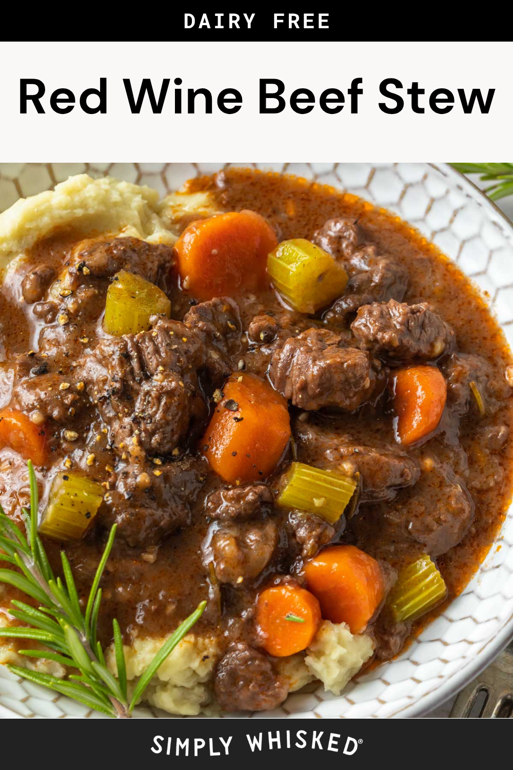 A plate of hearty red wine beef stew with carrots and celery is served over creamy mashed potatoes, garnished with a sprig of rosemary. This flavorful dish is labeled dairy free.