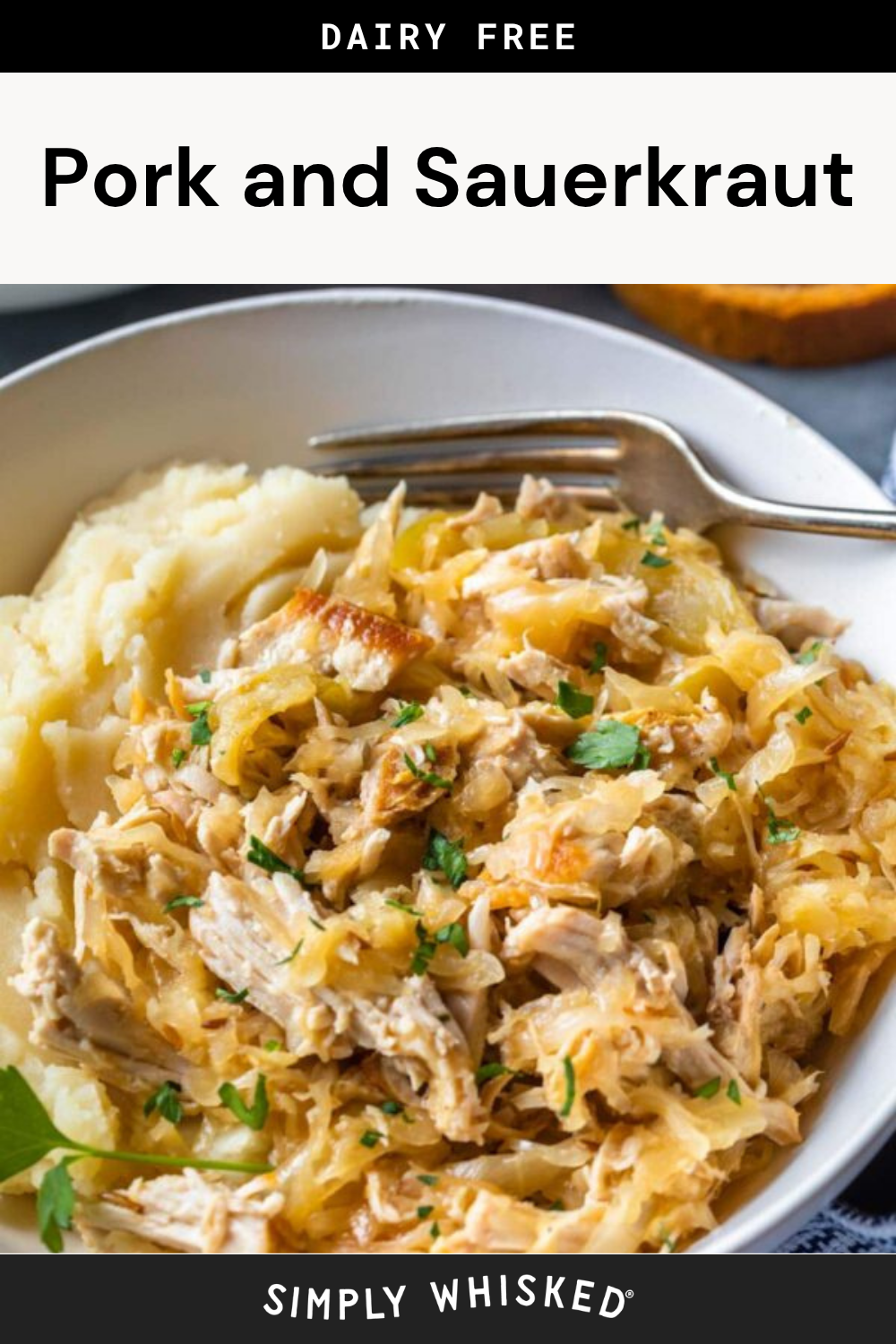 A bowl of savory pork and sauerkraut mixed together, garnished with fresh parsley and served beside creamy mashed potatoes. A fork rests on the side of the bowl, ready for you to enjoy this comforting meal.