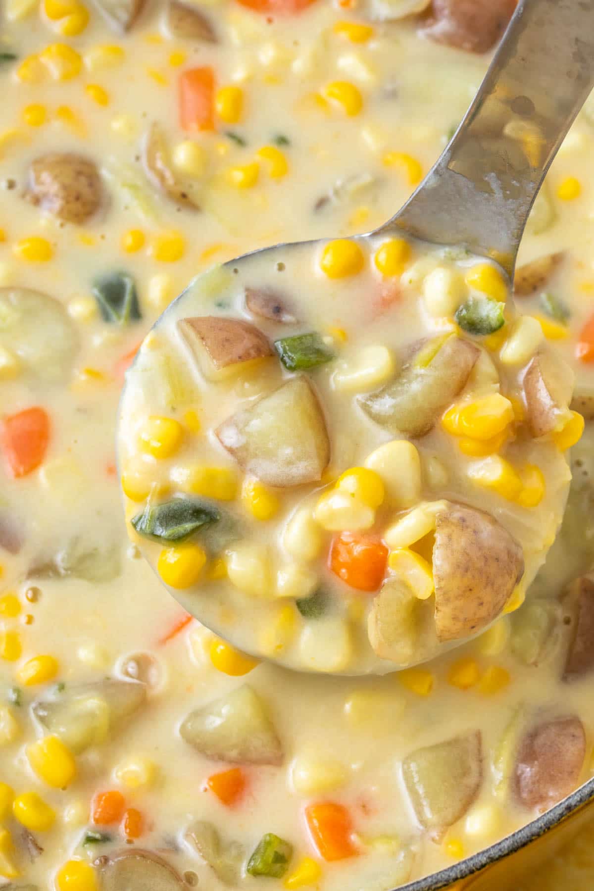 extreme close up view of potato corn chowder in a ladle scoop