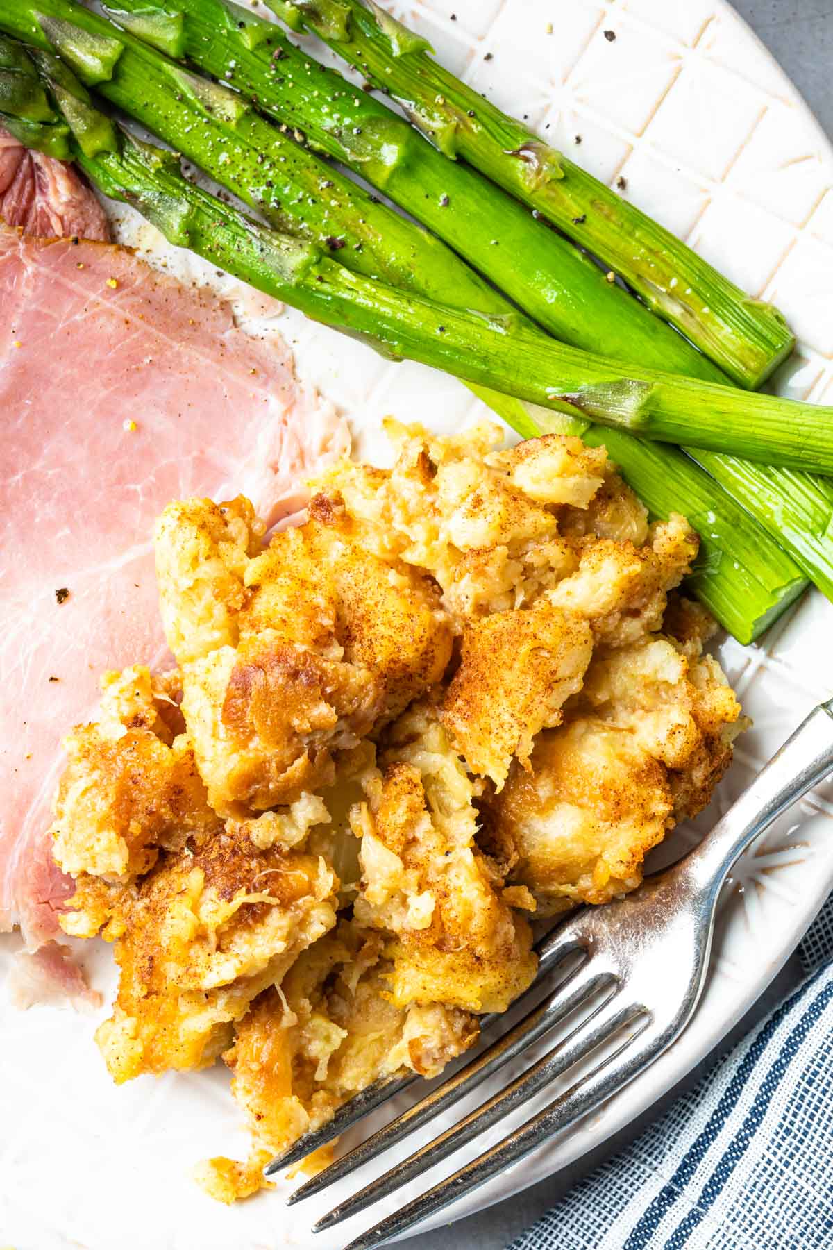 Close up of pineapple stuffing on a plate ham and asparagus with a fork
