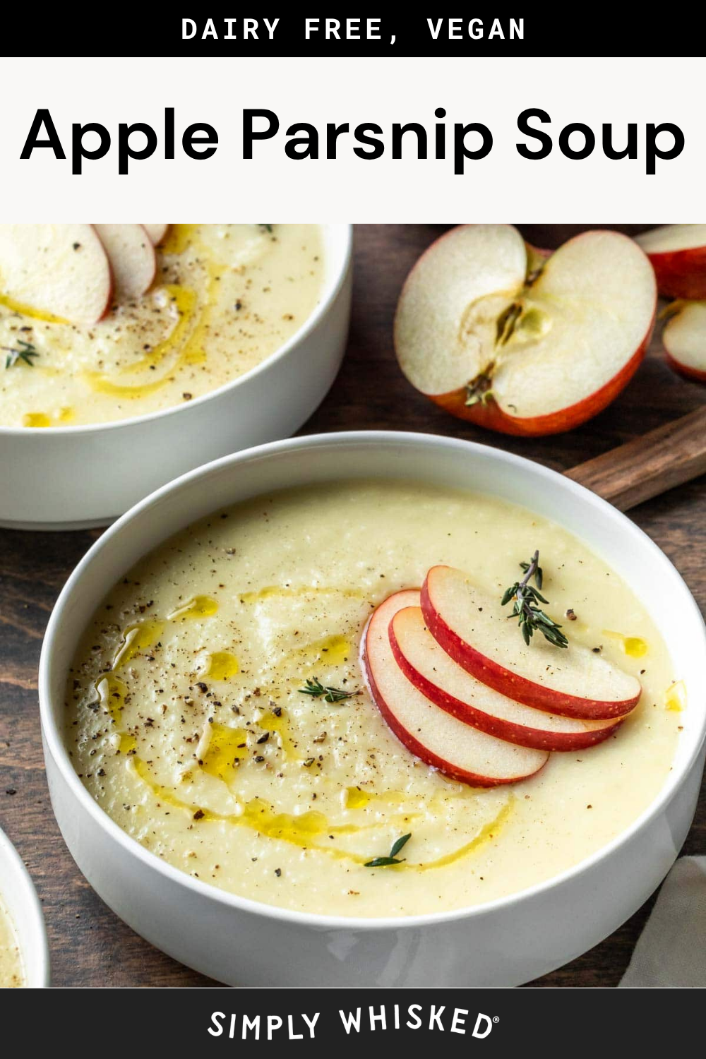 A bowl of creamy apple parsnip soup garnished with apple slices, fresh herbs, cracked pepper, and a drizzle of oil, with extra apple slices and another serving of the delicious apple parsnip soup on the side.