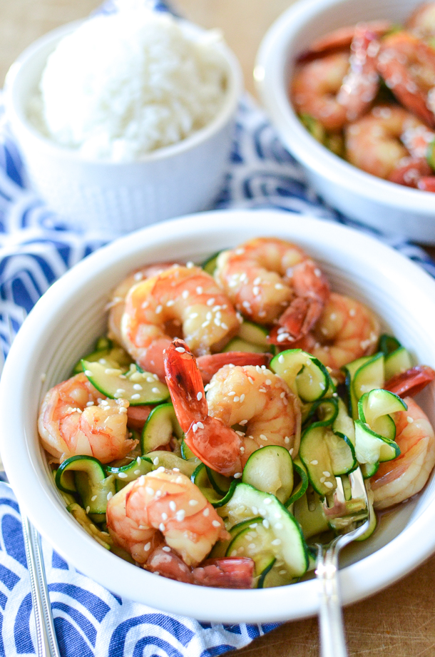 Honey garlic shrimp in a bowl with zucchini ribbons, garnished with sesame seeds. 