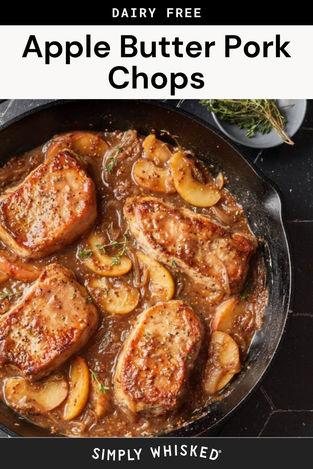 Pork chops cooked in a skillet with apple slices, onions, and a rich apple butter sauce. Fresh herbs garnish the dish. The text above reads Dairy Free Apple Butter Pork Chops.