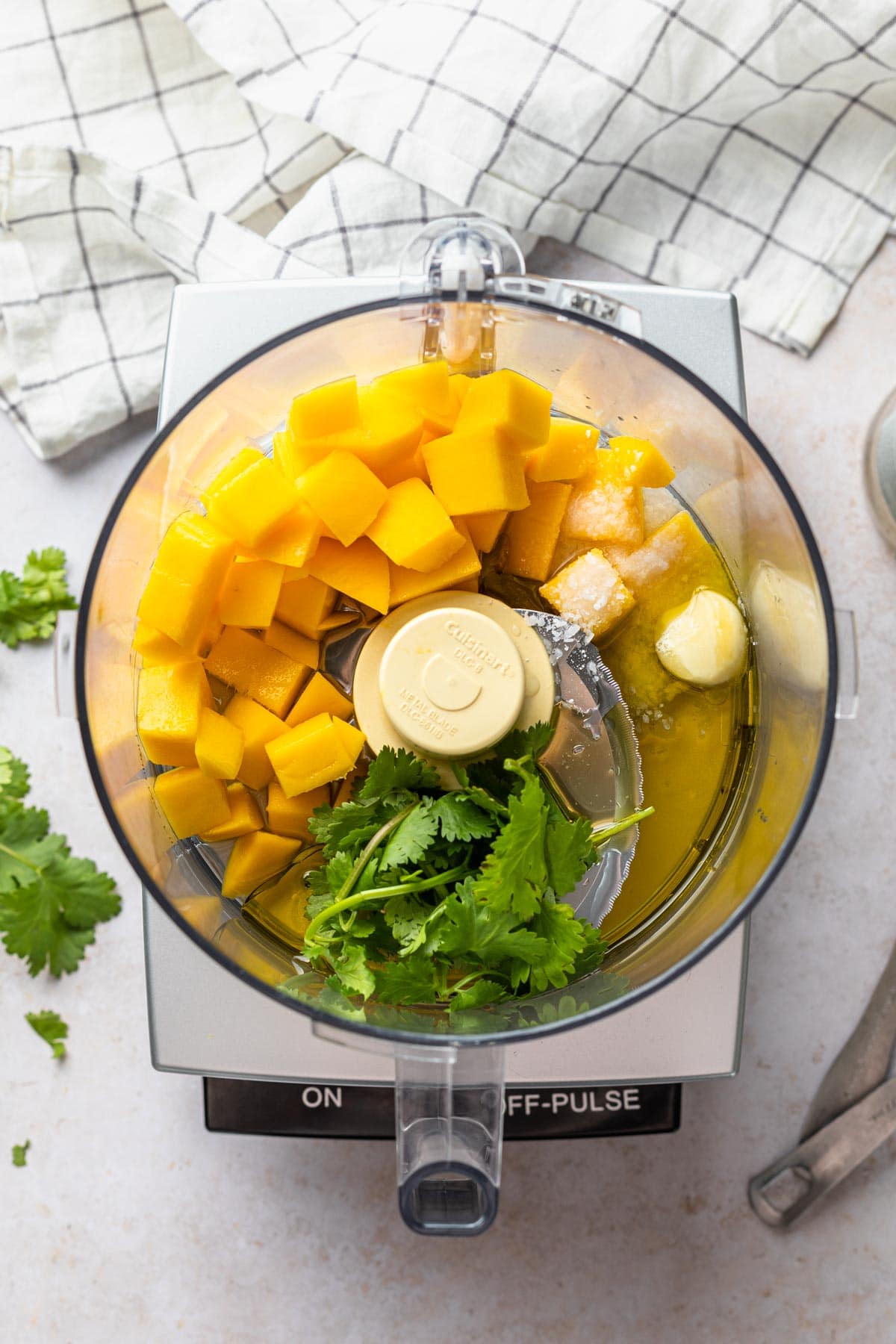 food processor with mango, cilantro, garlic and other ingredients for dressing. 
