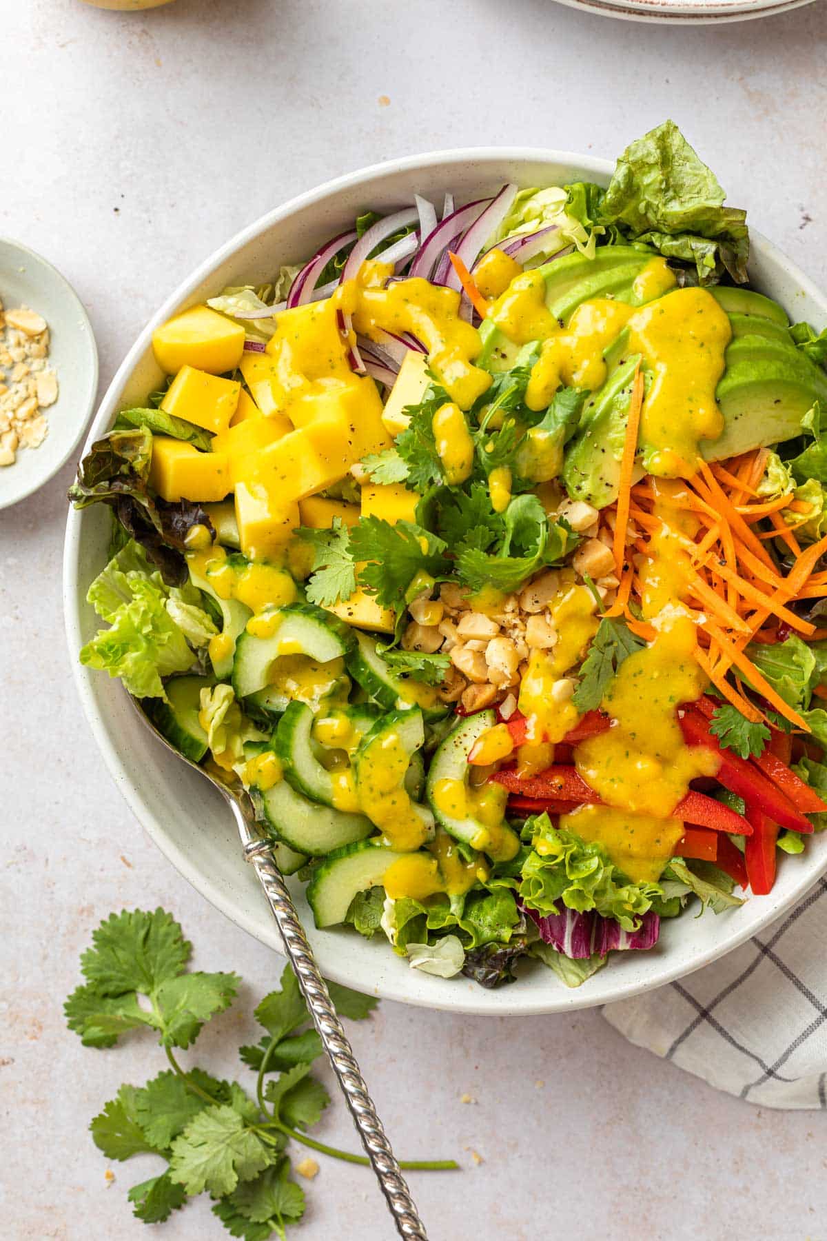 A serving bowl of salad with mango dressing. 