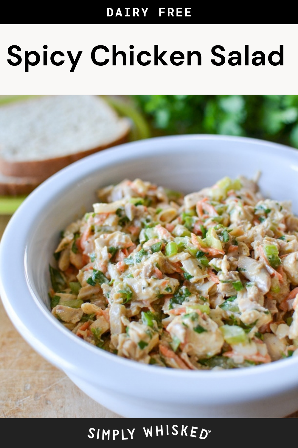 A white bowl filled with spicy chicken salad is in focus, showcasing the vibrant mix of flavors that define this dish. Sliced bread and fresh herbs are blurred in the background, drawing attention to the bold presentation. The text above reads Dairy Free Spicy Chicken Salad.