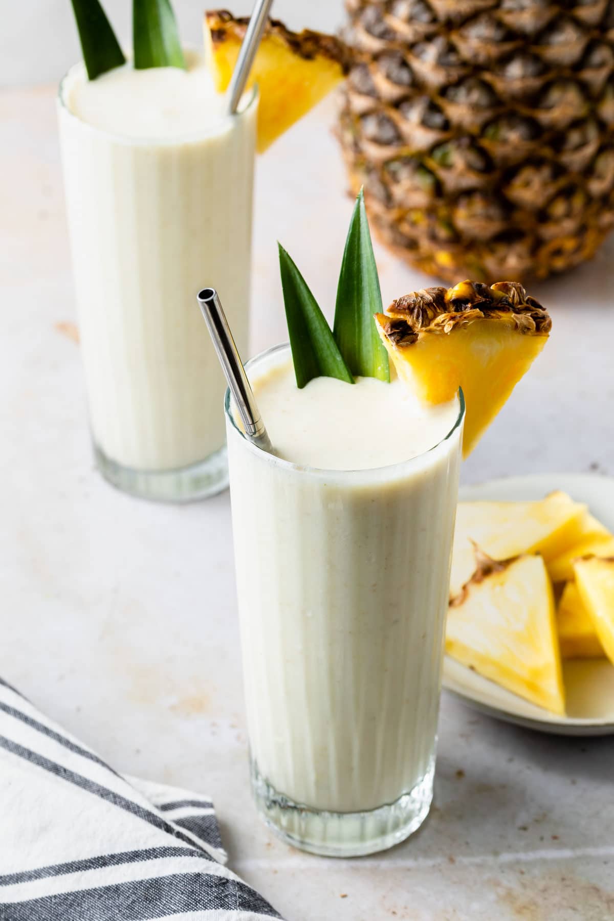 pineapple smoothies garnished with pineapple leaves and wedges