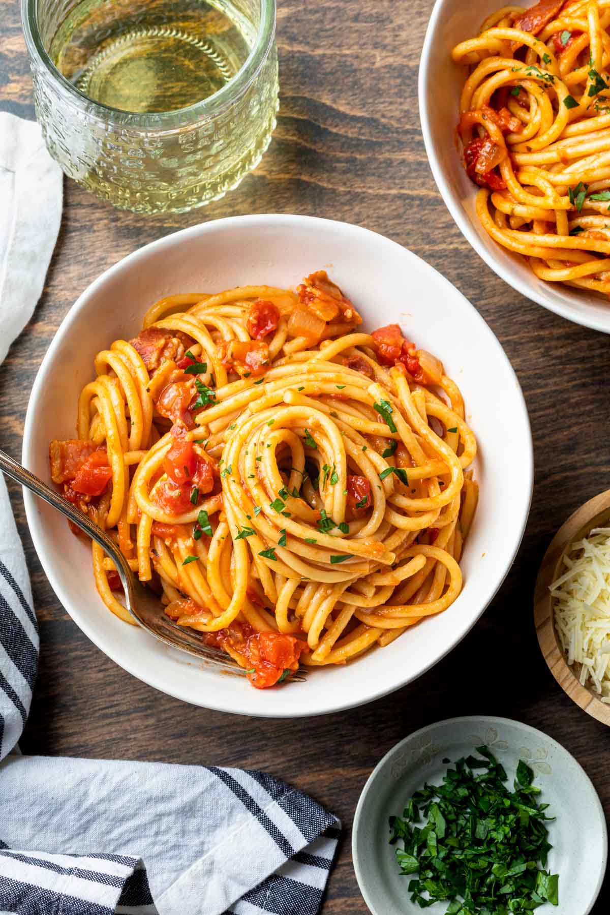 2 bowls of bucatini with sweet onion & pancetta and a glass of white wine. 