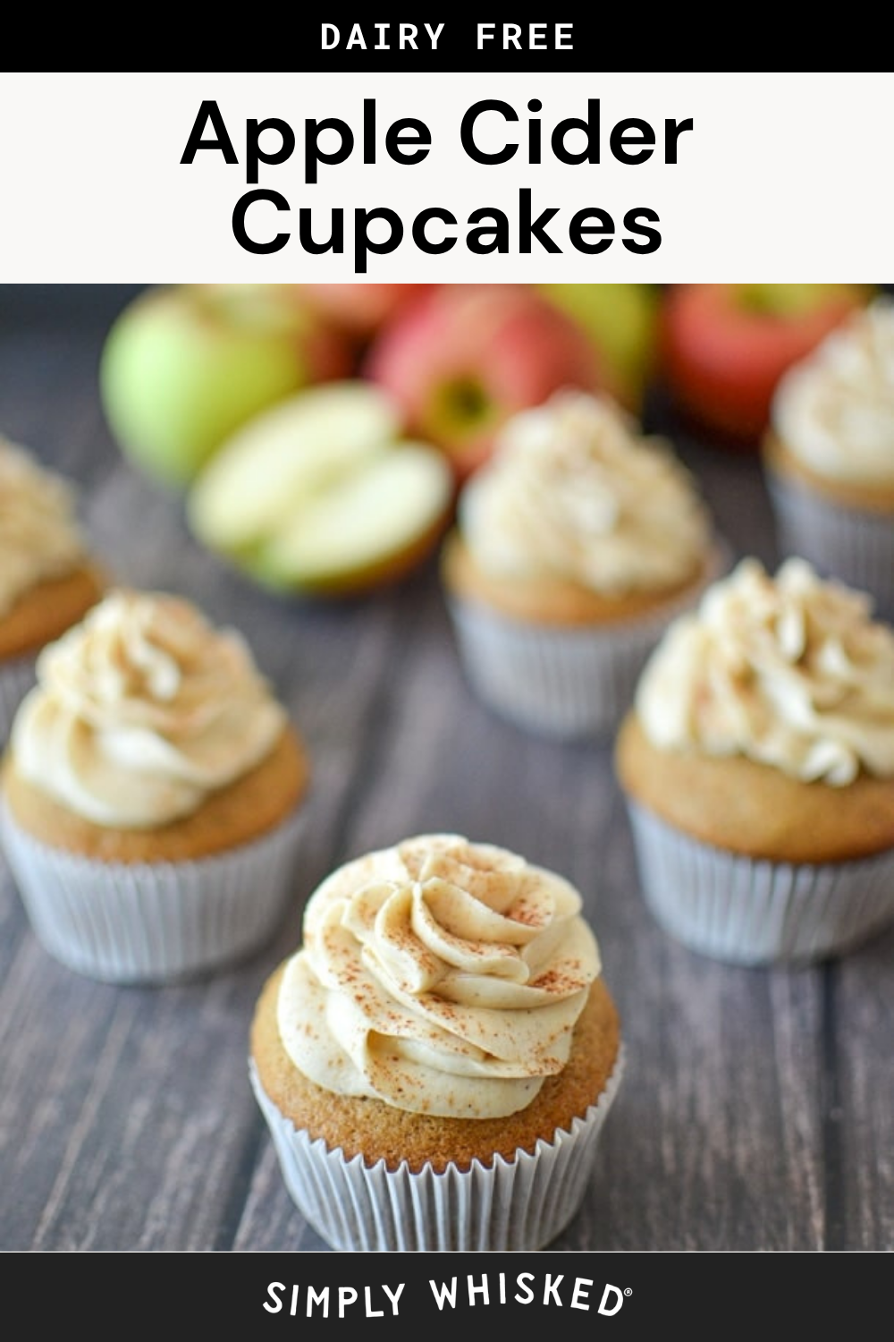Frosted apple cider cupcakes in white wrappers are displayed on a wooden surface with whole and sliced apples in the background. Text reads Dairy Free Apple Cider Cupcakes, highlighting the delicious flavors of these apple cider cupcakes.