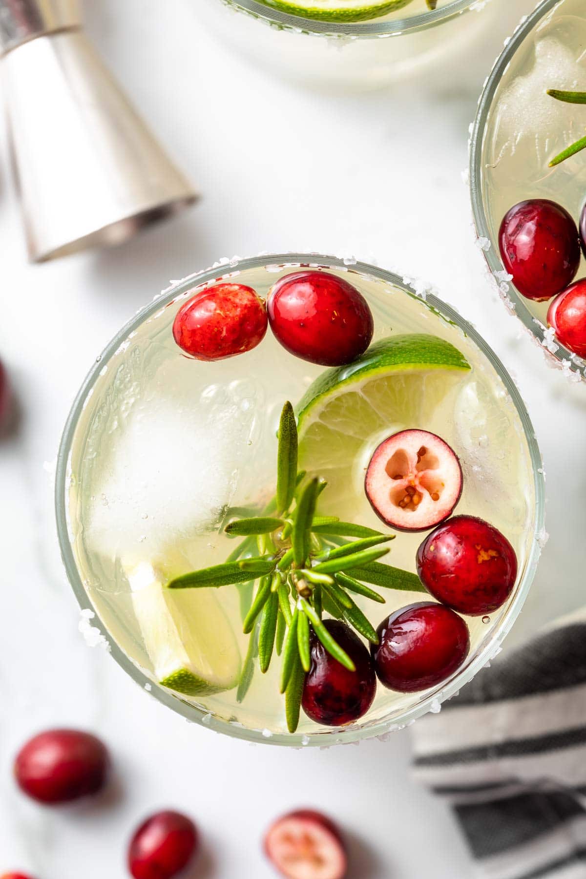 overhead close up of white christmas margarita garnished with cranberries, lime slice, and rosemary sprig