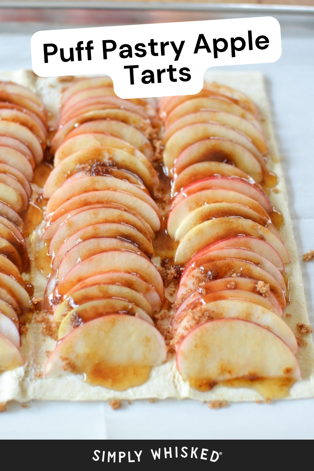 Sliced apples are artfully arranged on a sheet of puff pastry, then sprinkled with brown sugar and drizzled with syrup to create irresistible puff pastry apple tarts. The text reads Puff Pastry Apple Tarts. At the bottom, it says Simply Whisked.