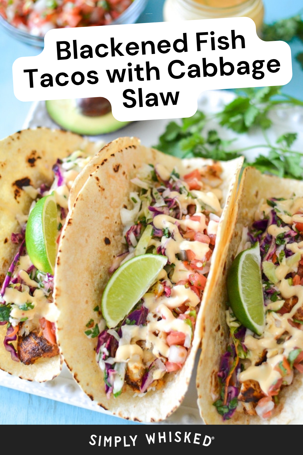 Three blackened fish tacos topped with cabbage slaw, diced tomatoes, creamy sauce, and lime wedges on flour tortillas are served on a white plate. A logo at the bottom reads “SIMPLY WHISKED,” highlighting these flavorful blackened fish tacos.