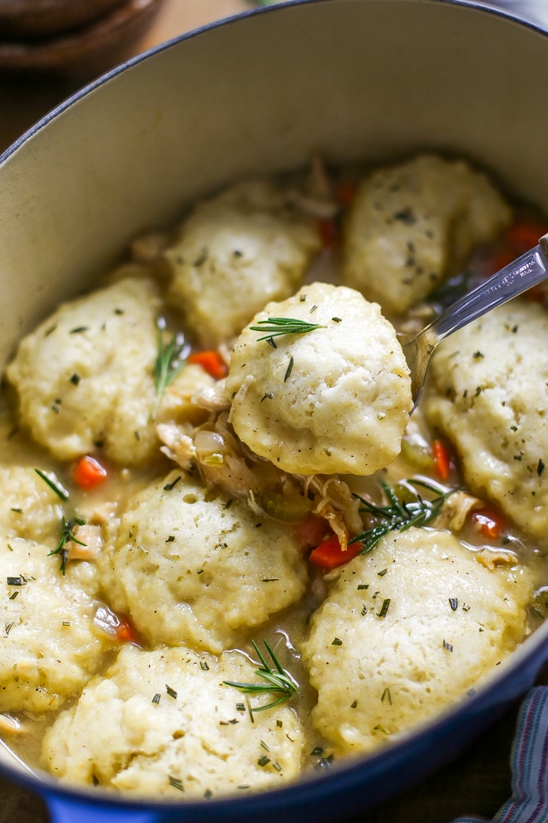close up of a dumpling on a spoon over a dutch oven full of chicken and dumplings