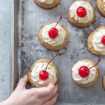 Pineapple cookies topped with pineapple frosting and maraschino cherries