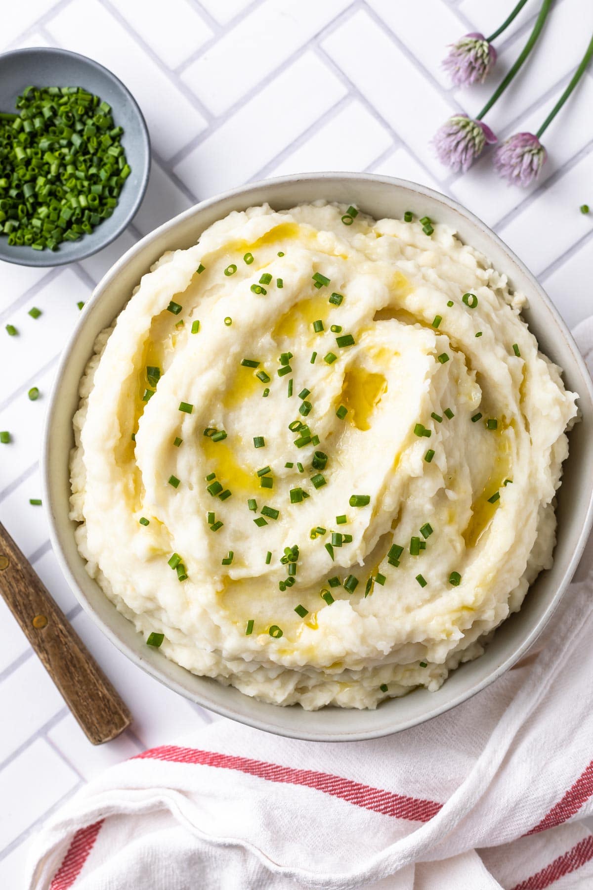 mashed potatoes drizzled with olive oil and garnished with chives on a tile surface