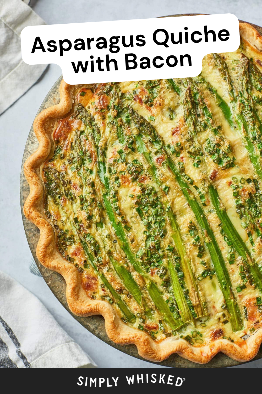 A close-up of an asparagus quiche with bacon in a golden pie crust, topped with whole asparagus spears and chopped herbs. Text reads Asparagus Quiche with Bacon and Simply Whisked. Linen napkins are nearby, highlighting the fresh ingredients in this delicious asparagus quiche.