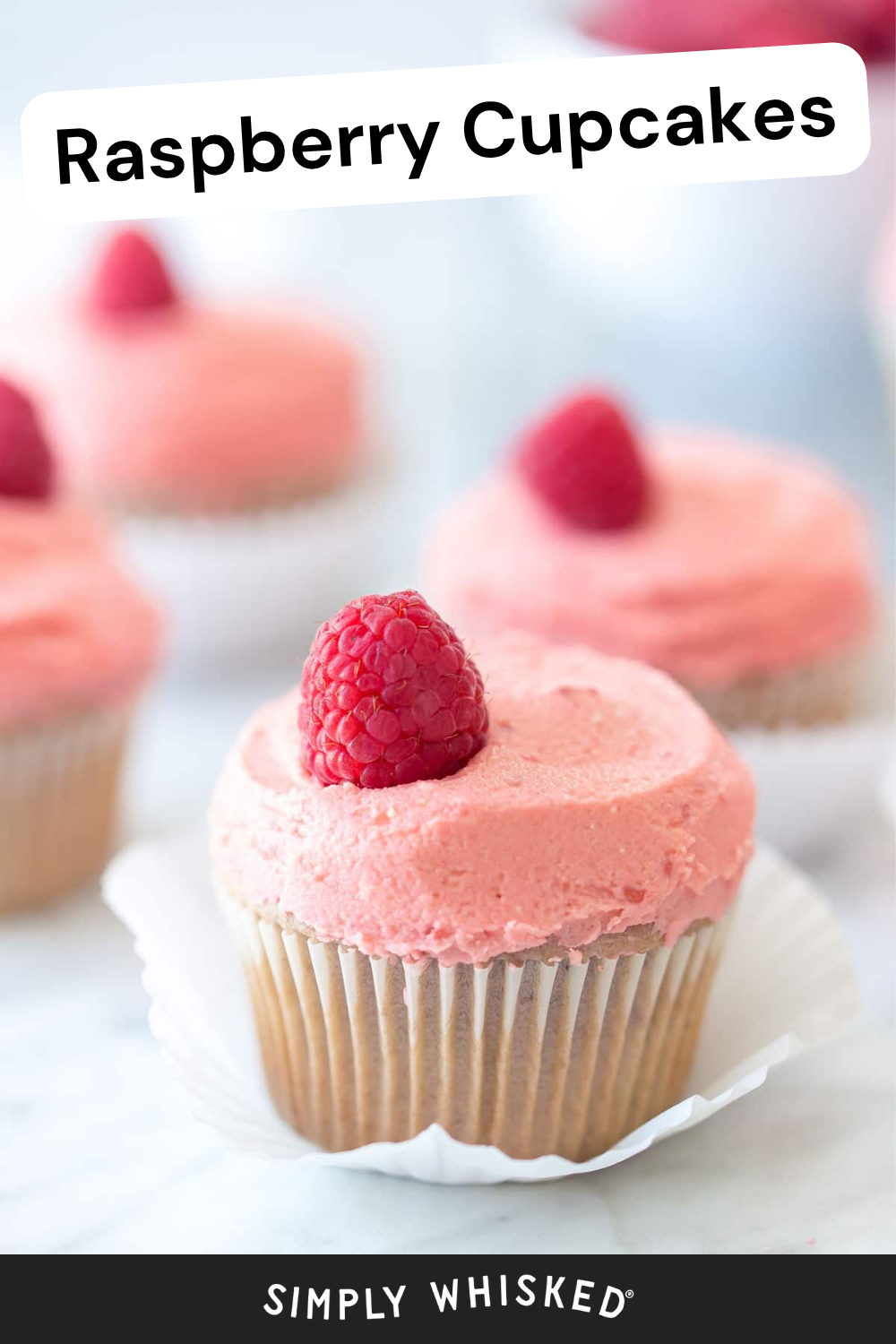 A close-up of delicious raspberry cupcakes with pink frosting and a fresh raspberry on top. The text Raspberry Cupcakes appears at the top, and Simply Whisked is at the bottom.