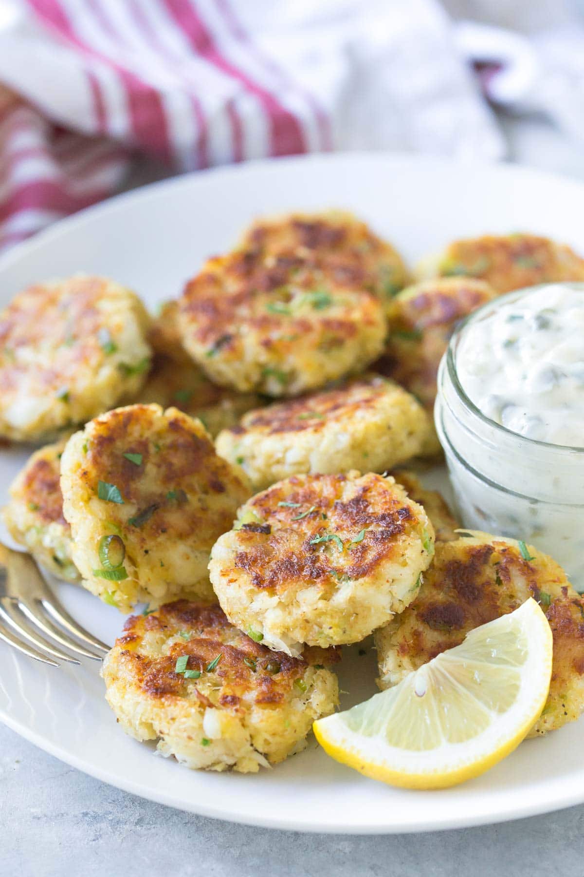 Fish Cakes on a white plate with a lemon slice and tartar sauce