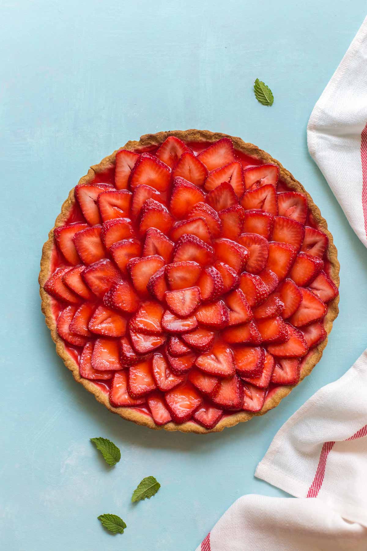 strawberry tart on a blue background with mint leaves 