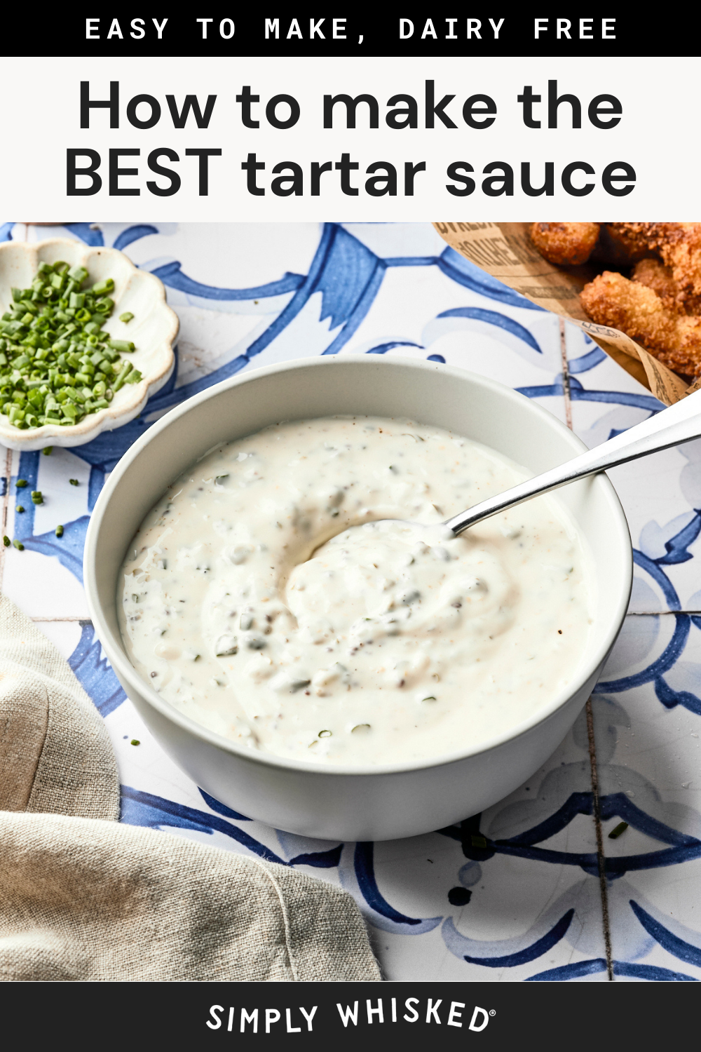 A bowl of creamy homemade tartar sauce with a spoon sits on a blue and white tiled surface beside chopped chives and breaded food. Text at the top and bottom reads How to make the BEST tartar sauce recipe.