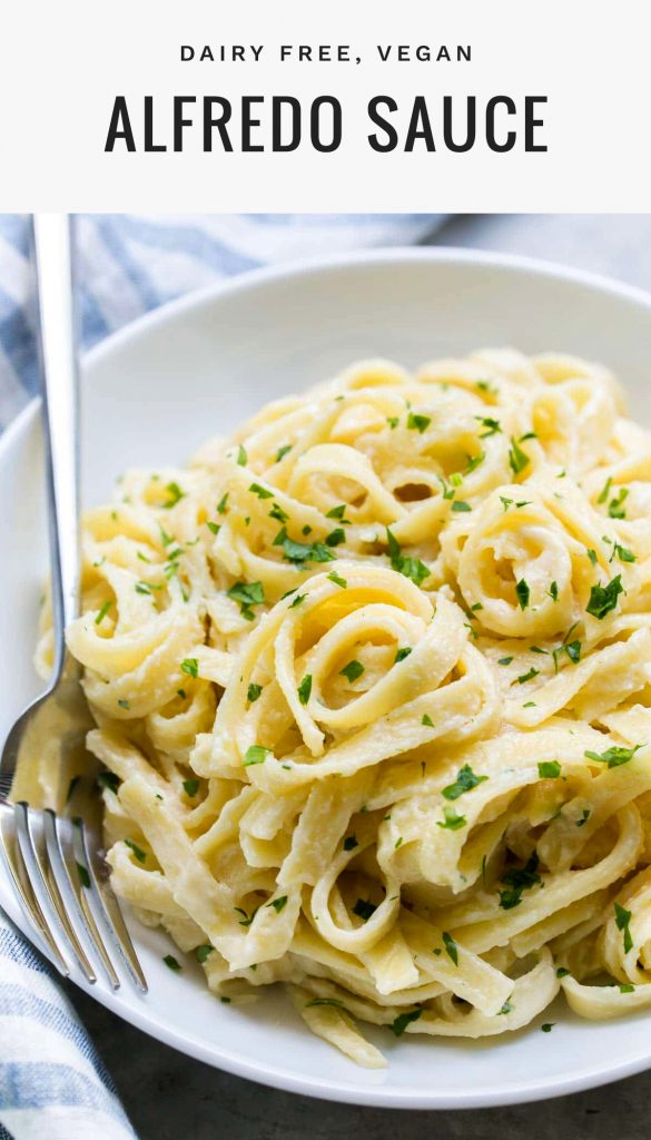 close up of dairy free alfredo sauce on fettuccini in a white bowl topped with chopped parsley