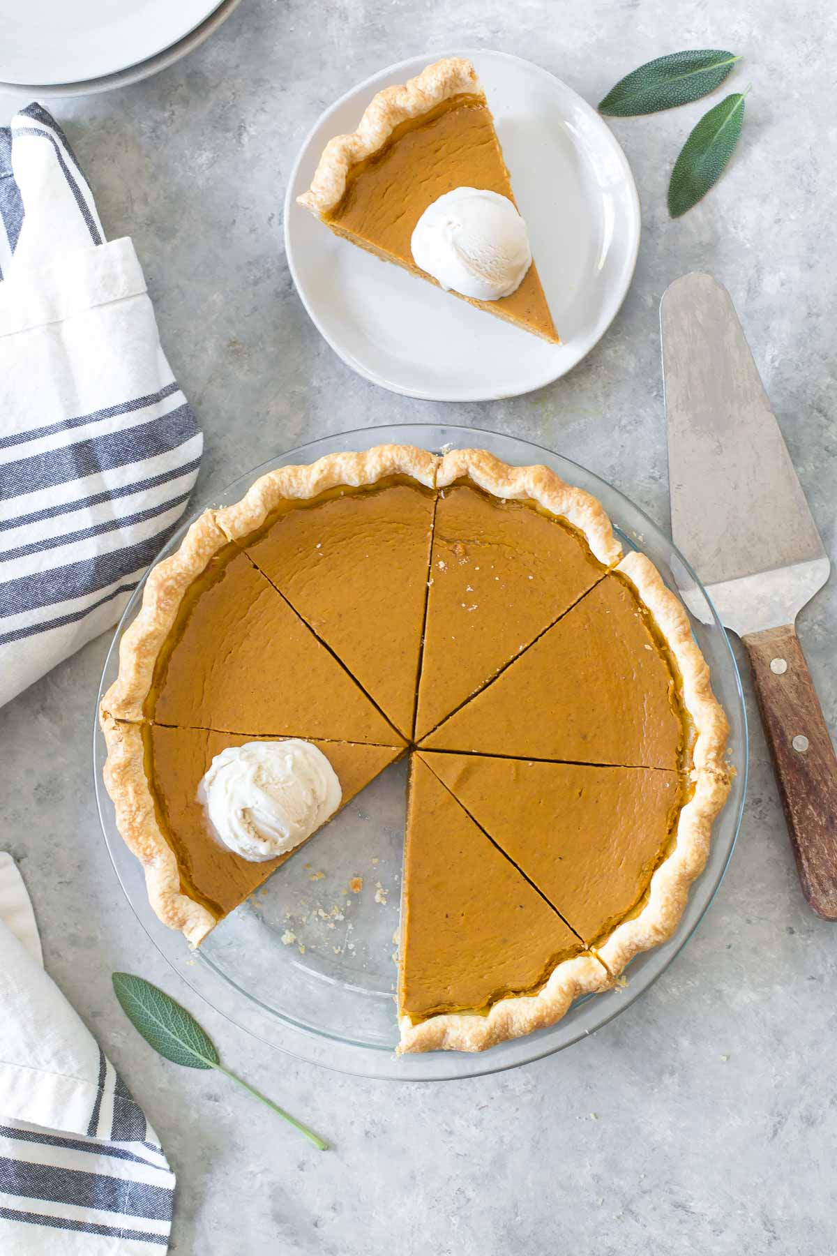 overhead shot of a dairy free pumpkin pie, sliced, one piece removed and sitting on a plate next to the pie dish