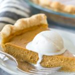 closeup of a slice of dairy free pumpkin pie topped with a scoop of melting dairy free vanilla ice cream