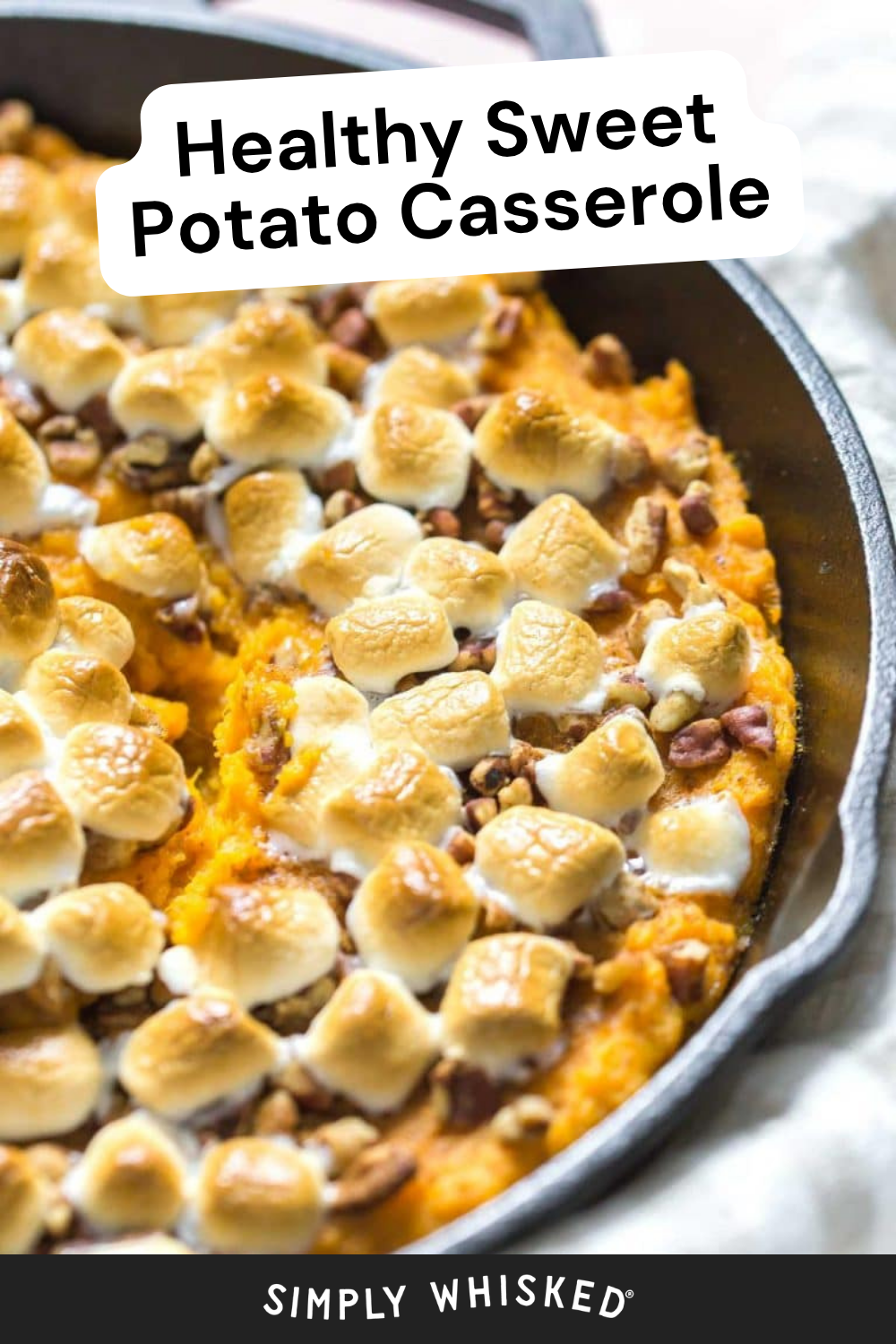A skillet filled with healthy sweet potato casserole, topped with toasted marshmallows and chopped nuts. Text overlay reads Healthy Sweet Potato Casserole.