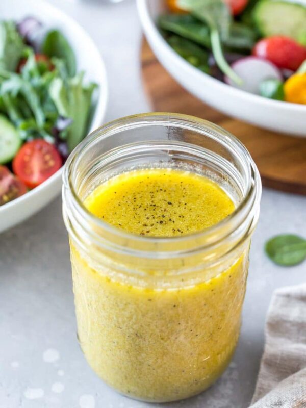 Easy Dijon vinaigrette in a mason jar with two salads in the background