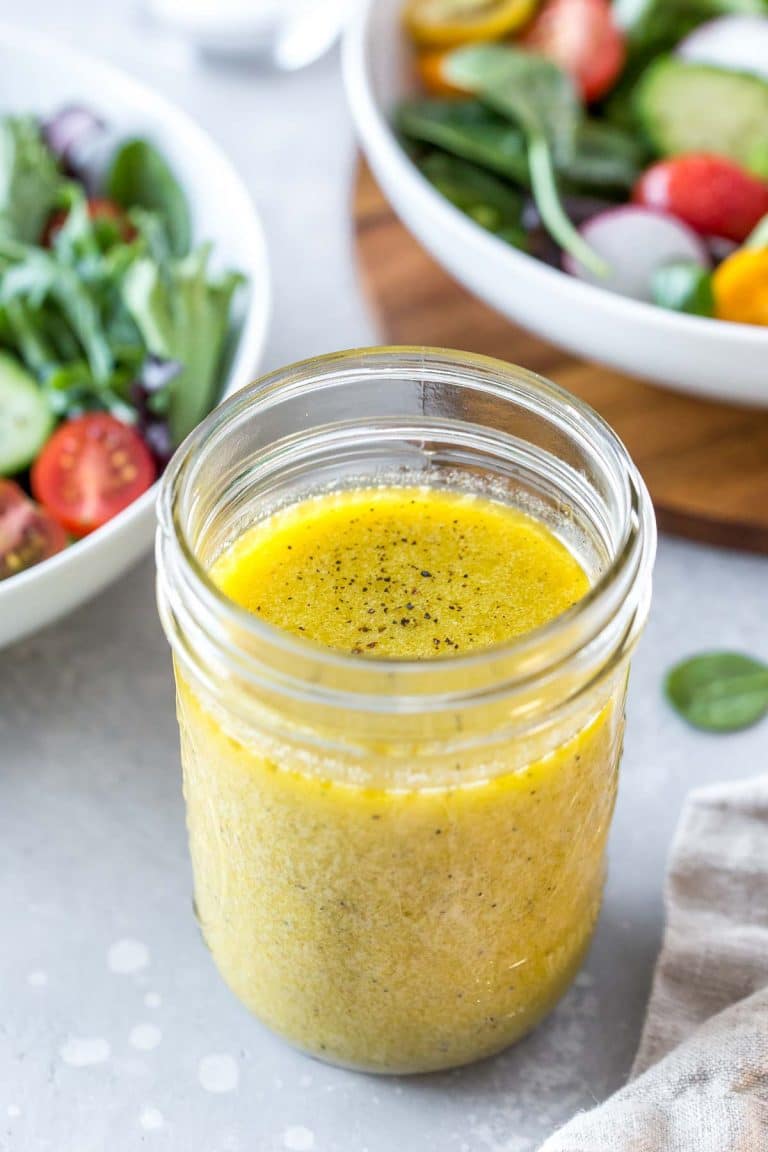 Easy Dijon vinaigrette in a mason jar with two salads in the background