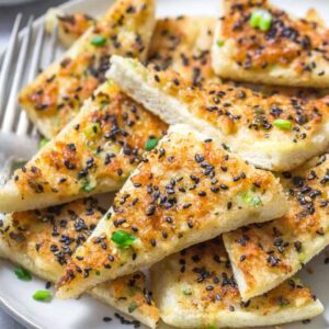 closeup of a plate with Chinese shrimp toast points topped with black sesame seeds