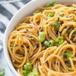 sesame noodles in a white bowl topped with green onion and black sesame seeds, optimized for Pinterest with text overlay