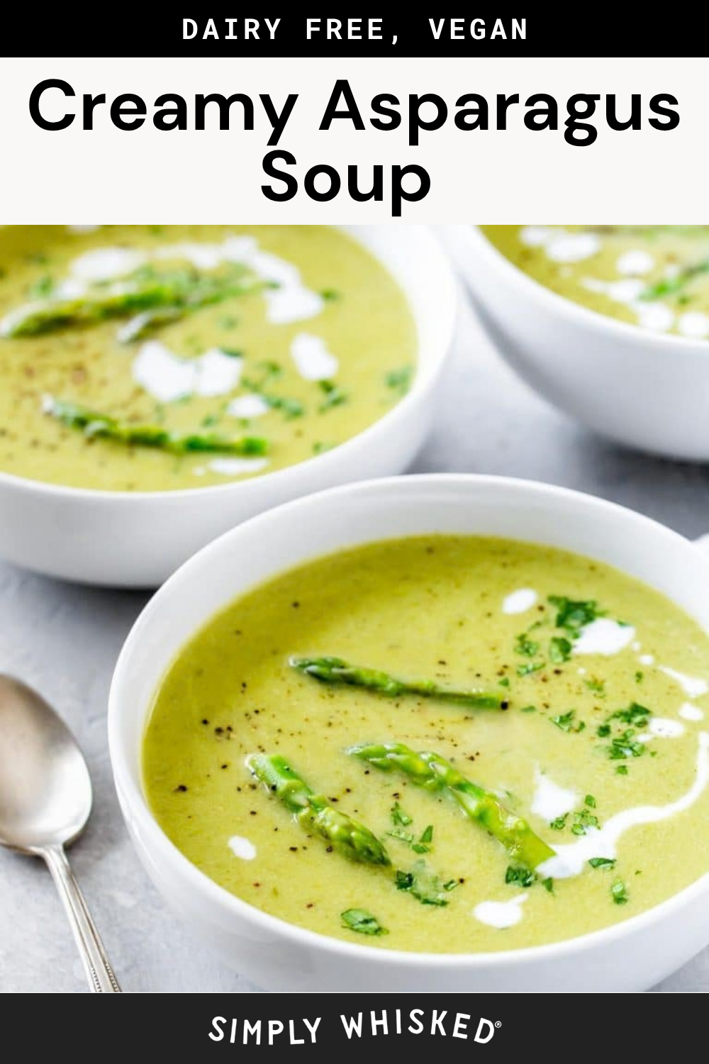 Three white bowls filled with creamy asparagus soup, garnished with asparagus tips, fresh herbs, and a delicate white drizzle, sit on a light surface with a spoon nearby. Text above reads Creamy Asparagus Soup – Dairy Free, Vegan.