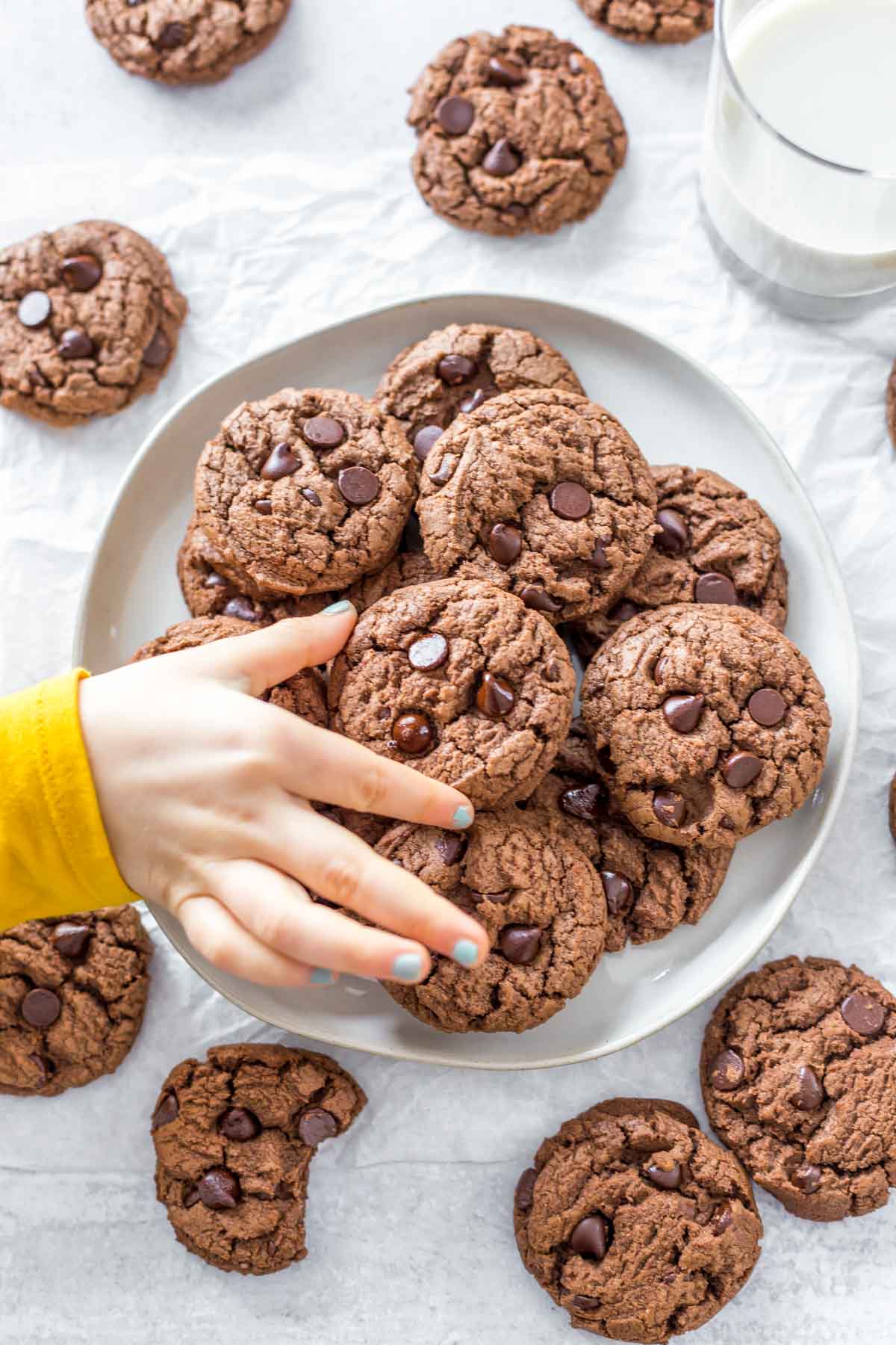 A child's hand picking up a cookie from a serving platter.
