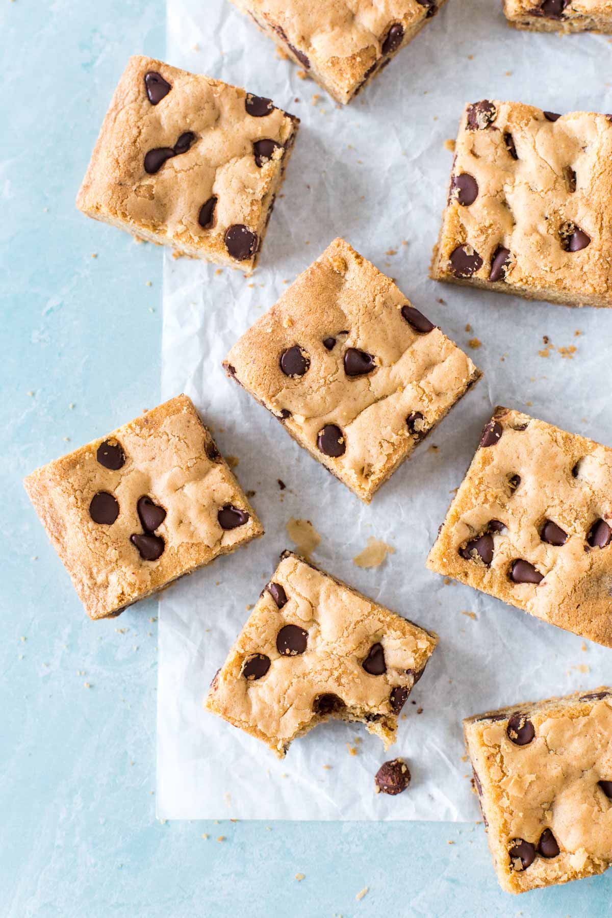 chocolate chip cookie bars on a piece of parchment paper on a light blue surface